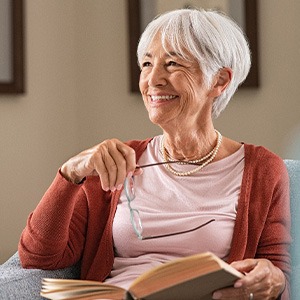 Smiling senior woman sitting in chair reading a book
