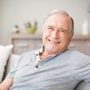Senior man in striped shirt sitting on couch and smiling