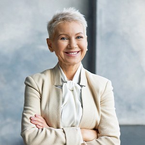 Senior woman in suit smiling with arms folded