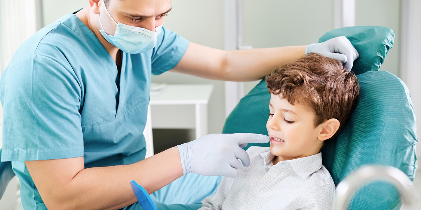 Young boy in the dental chair looking at his teeth in a mirror