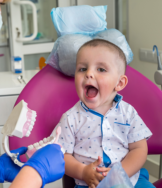 Toddler in the dental chair opening their mouth wide
