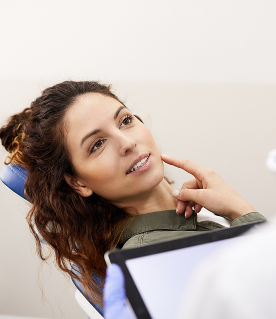 Woman touching her face while talking to her dentist