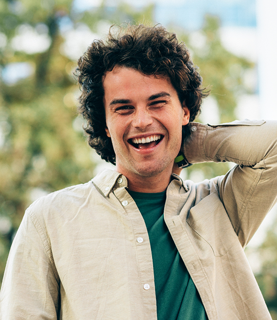 Man with curly brown hair smiling in the sun