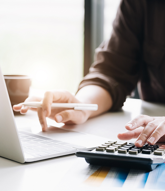 Person typing on a calculator at a desk