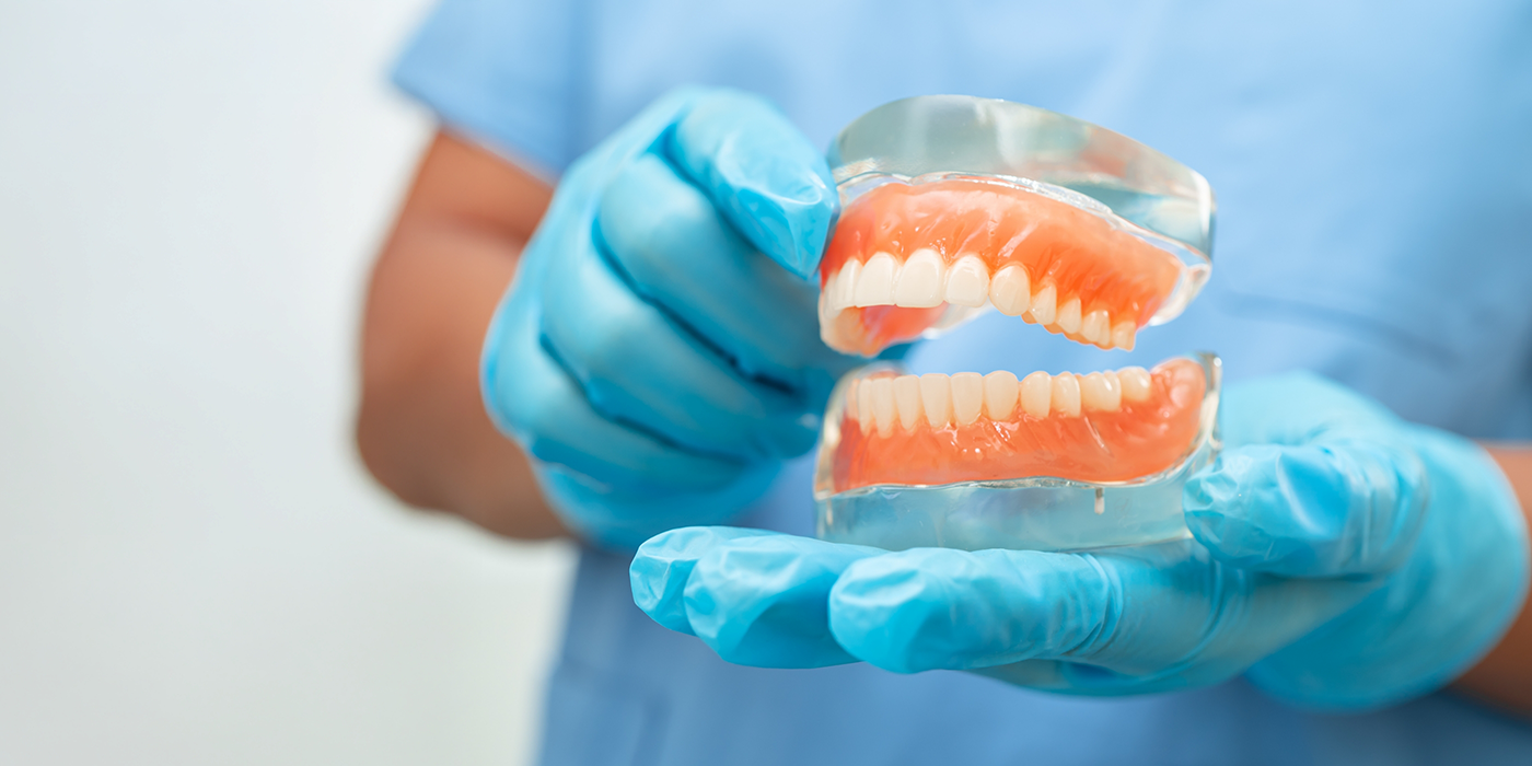 Dentist holding a set of dentures in Fort Worth