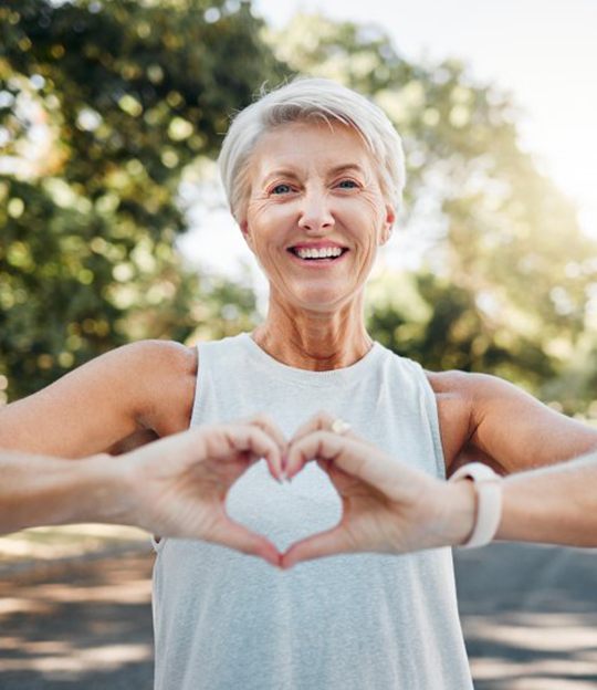 Smiling lady makes shape of heart with her hands