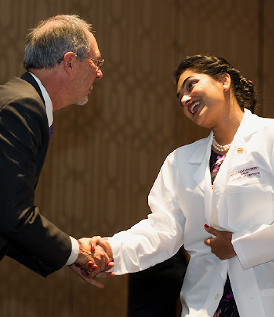 Doctor Patel in a white lab coat shaking hands with a man in a suit