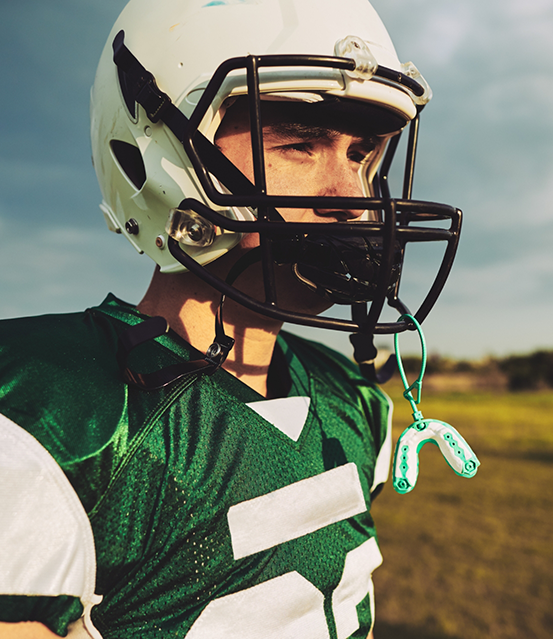 Football player with a mouthguard hanging from their helmet