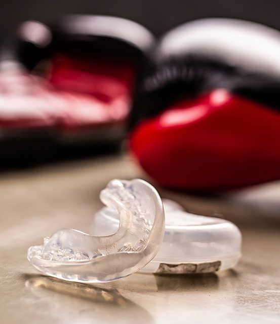 Clear mouthguard next to two boxing gloves