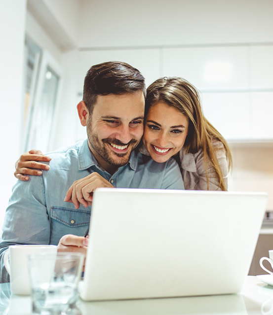 Man and woman smiling at a laptop