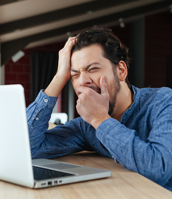 Man yawning at his work desk