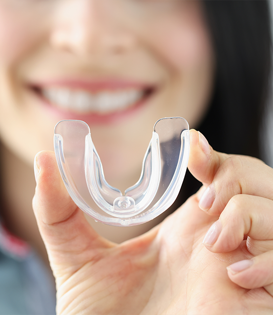 Smiling woman holding a clear nightguard