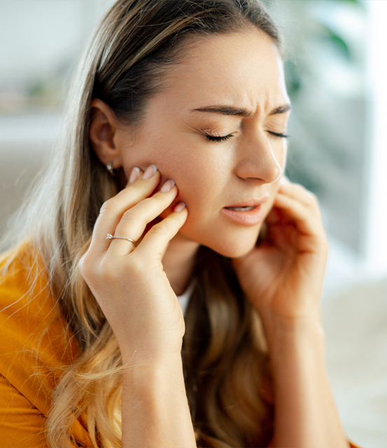 Woman holding both sides of her jaw in pain