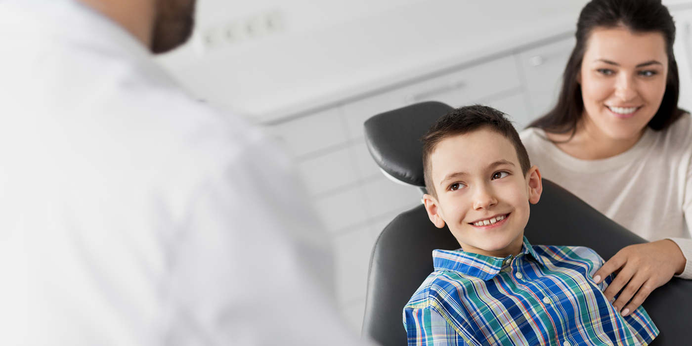 Young boy in the dental chair smiling at his dentist