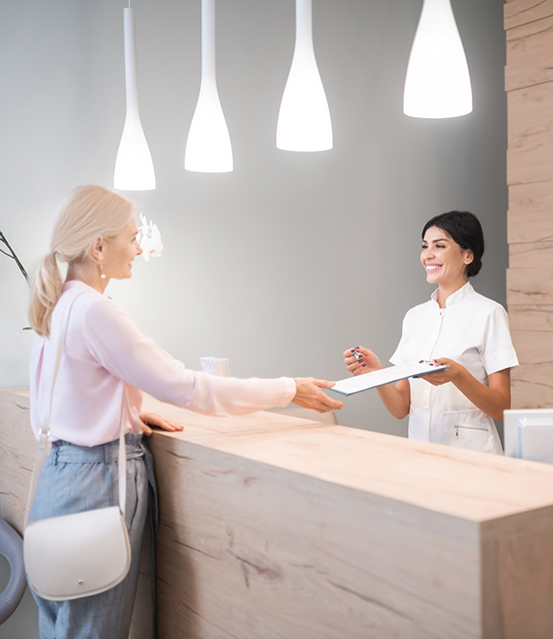 Woman checking in at the front desk of a dental office
