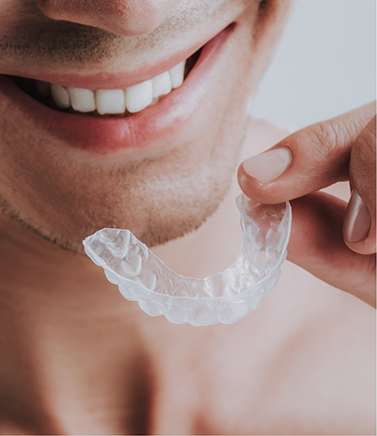 Man holding a clear nightguard near his smile
