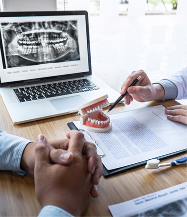 Person sitting across a desk from their dentist during a consultation