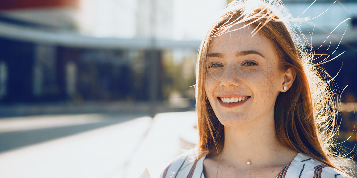 Young woman smiling outdoors after restorative dentistry treatment