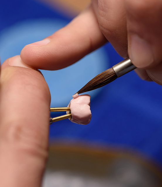 Close up of a dental crown being painted