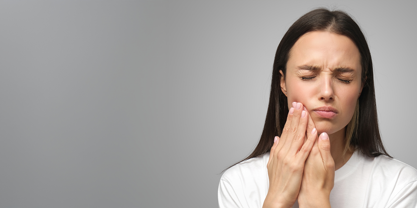 Woman holding the side of her jaw in pain before TMJ treatment in Fort Worth