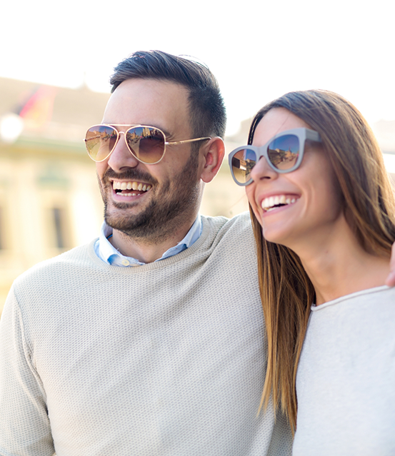 Man and woman smiling and wearing sunglasses outdoors